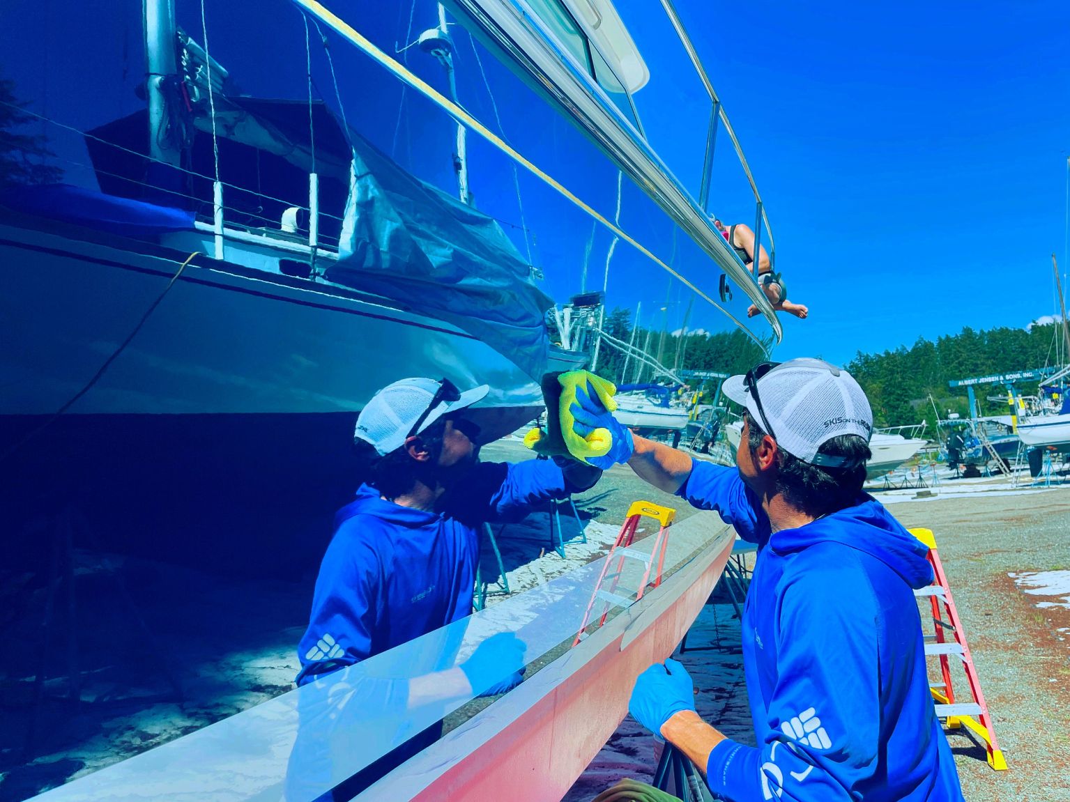 SeaStars detailer carefully polishing the reflective blue hull of a yacht